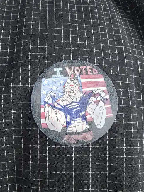 A circular, hand-drawn sticker on a black-and-white checkered shirt features a muscular, bearded, wolf-like creature flexing…