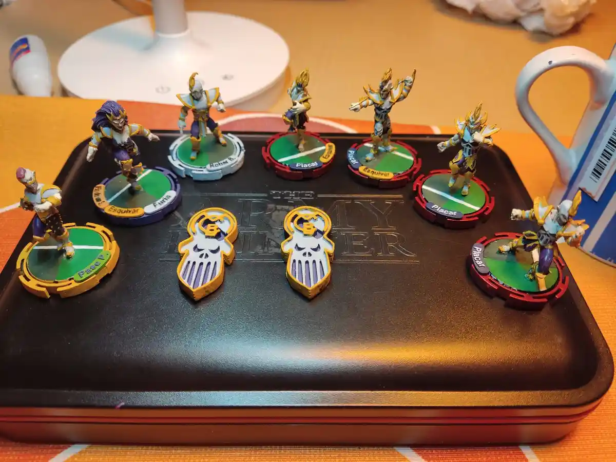 A photo of seven painted miniature figures on circular bases arranged on a black tray labeled 'THE ARMY BUILDER'. Two…