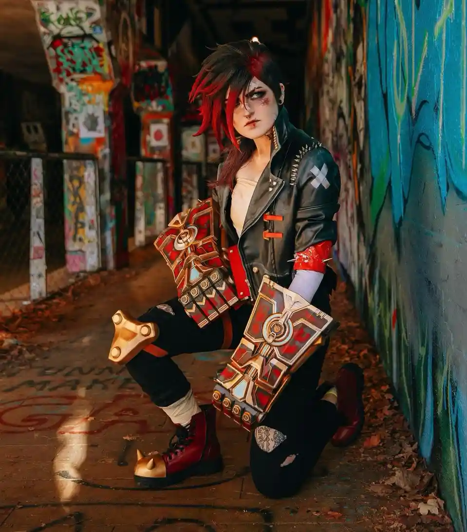 A person in a detailed cosplay of a character with red and black hair, wearing a black leather jacket with white cross…