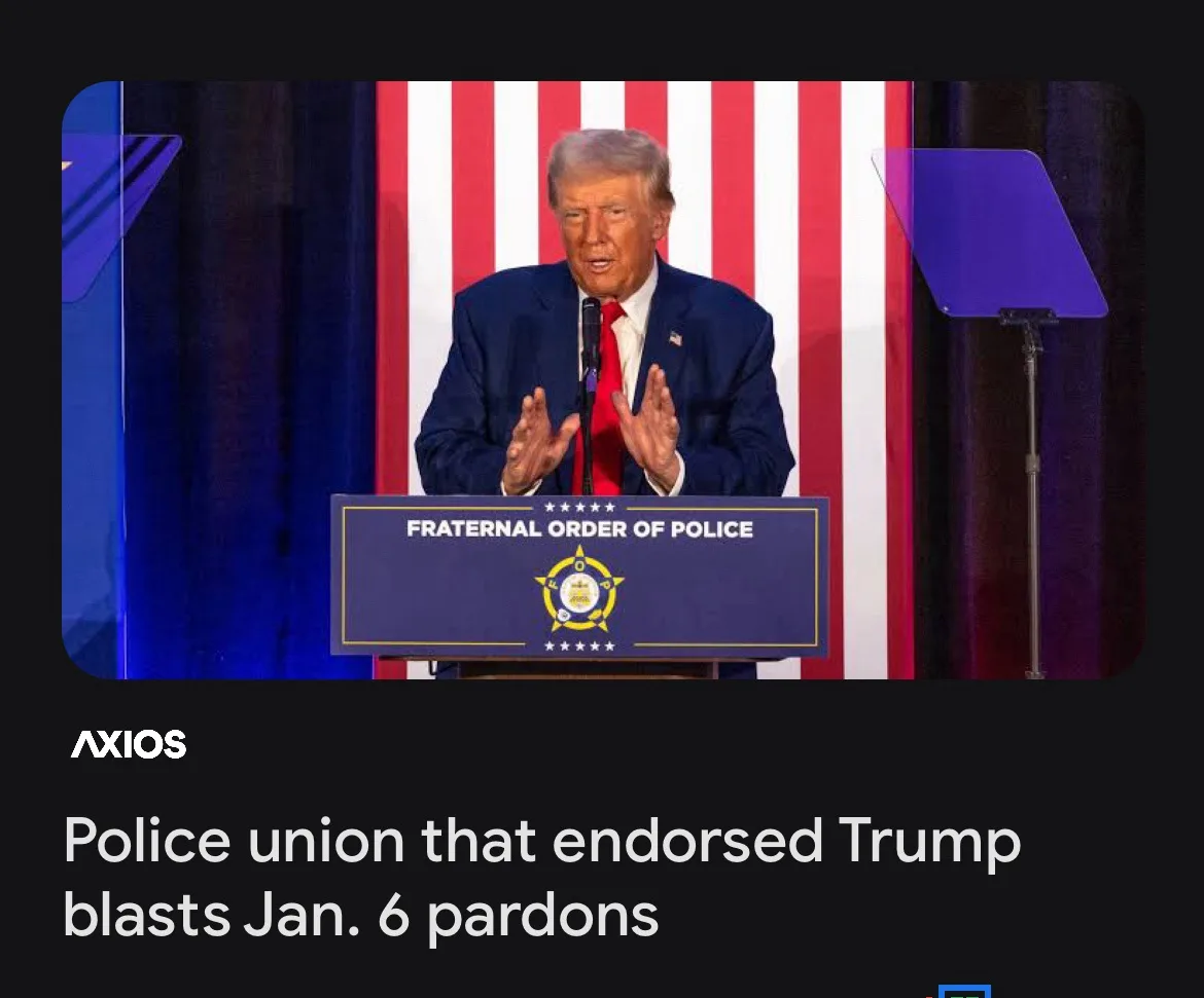 A man in a dark suit and red tie stands behind a podium labeled 'FRATERNAL ORDER OF POLICE' against a backdrop of red and…