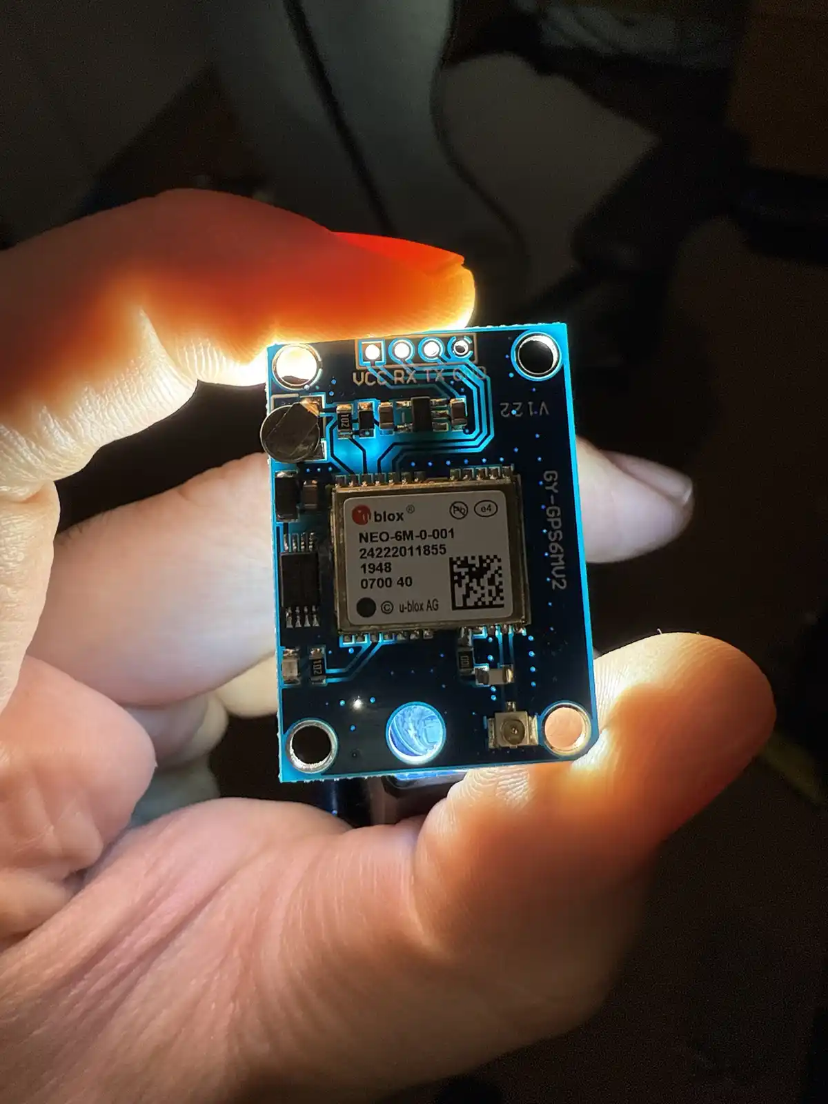 A hand holds a small blue electronic circuit board, a u-blox NEO-6M GPS module, with the year '1948' clearly visible printed…