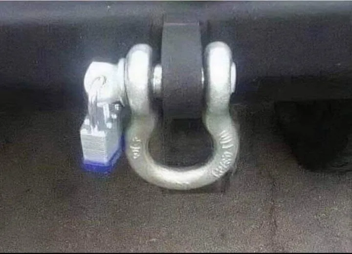 A close-up photo shows a large, silver-colored trailer hitch on the underside of a vehicle, with a small blue and silver…