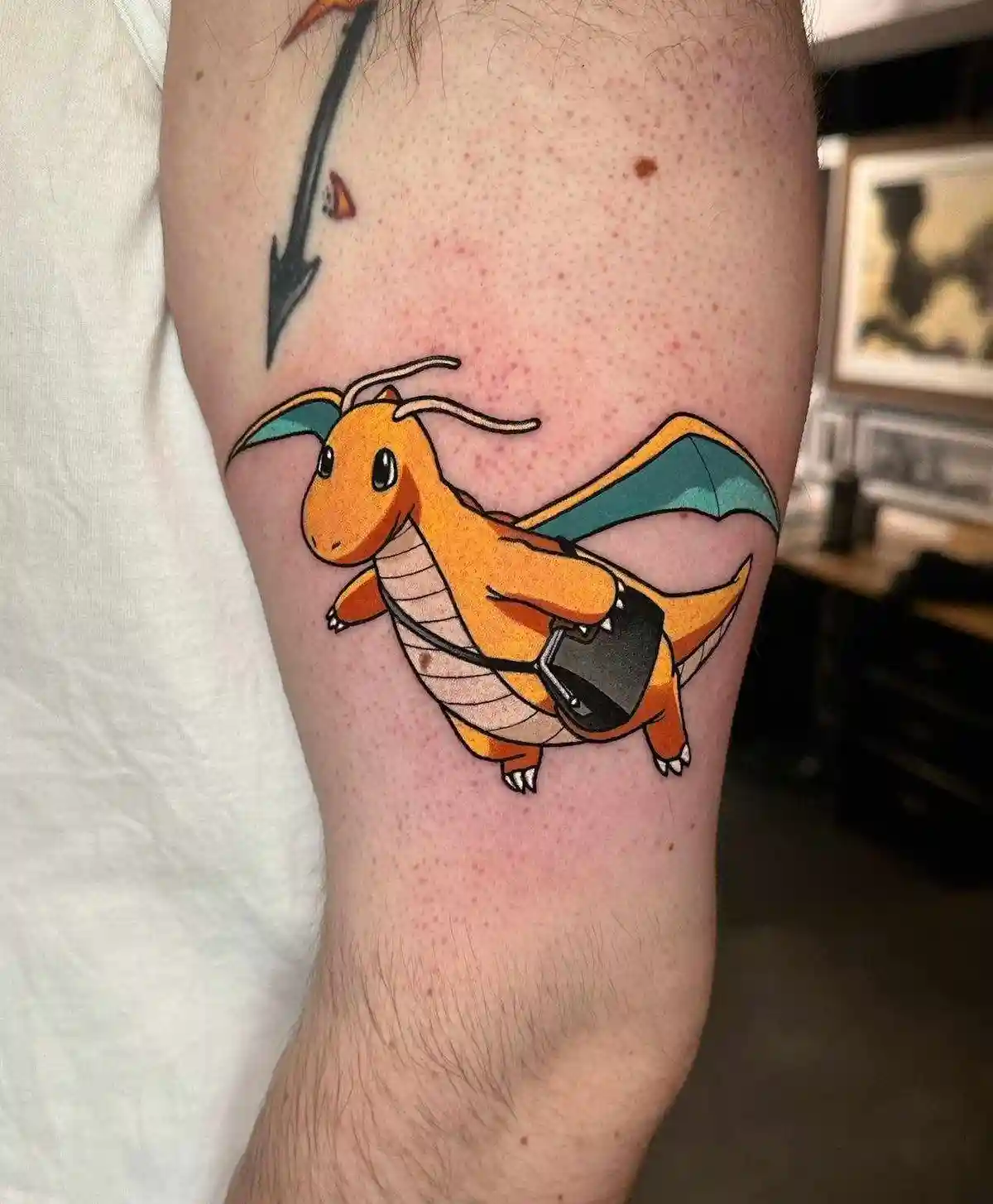 A close-up photo shows a tattoo on a person's upper thigh featuring the Pokémon Charmander, depicted in its classic orange…