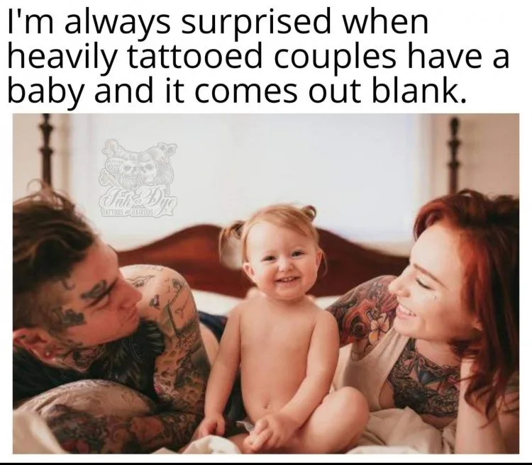 A photo shows a smiling baby sitting between two heavily tattooed parents on a bed. The father on the left and mother on the…