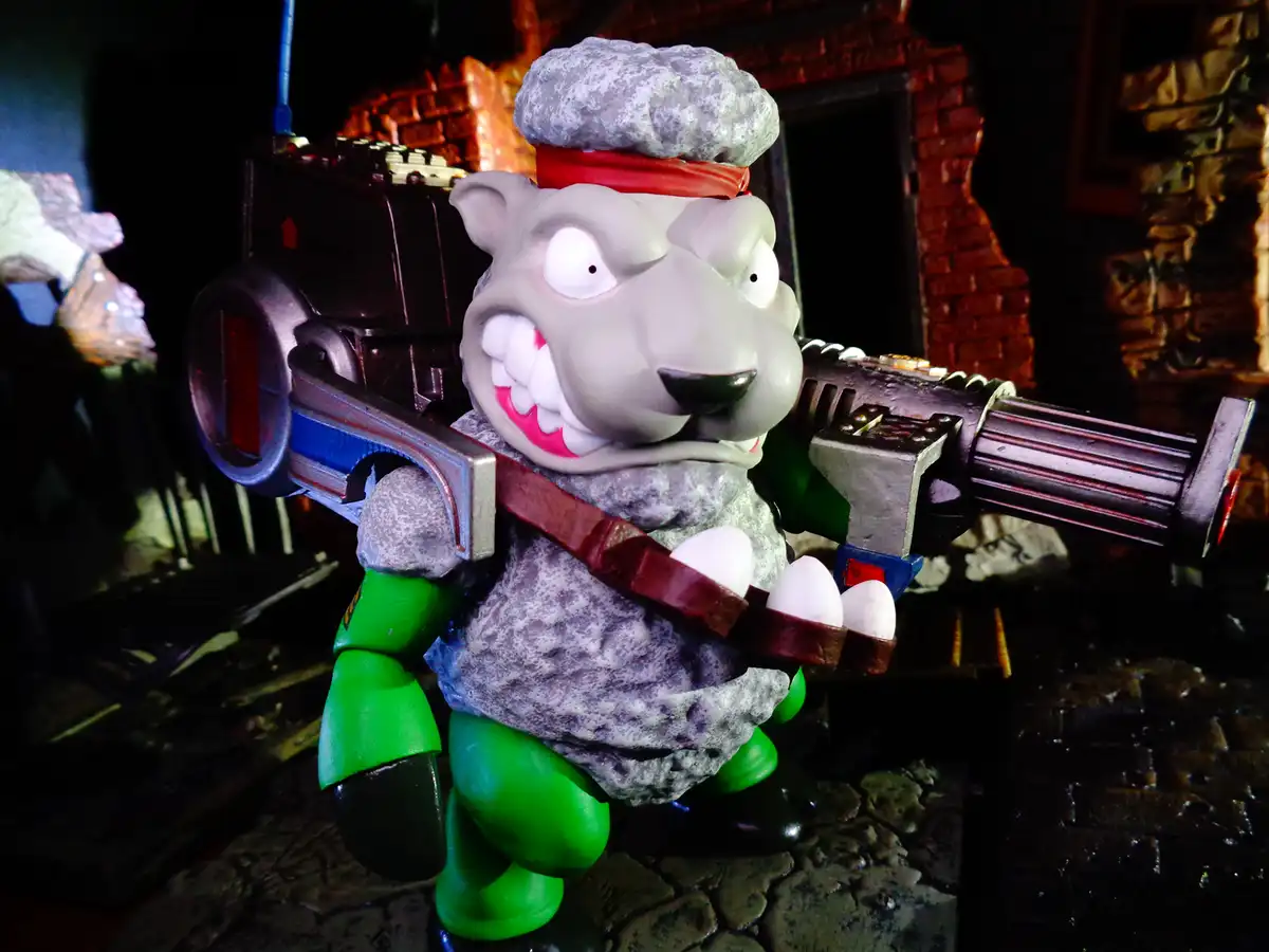 A figurine of a grey, cartoonish sheep-like creature with a rock-like texture, wearing a chef's hat and green pants, is…
