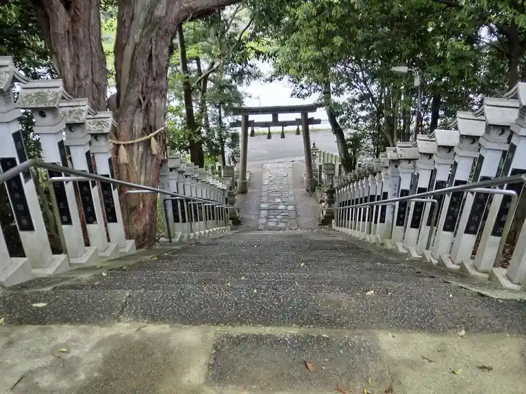 a steep stone staircase flanked by white stone railings with black plaques leads upward through a forested area toward a…