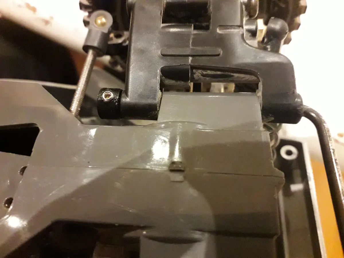 A close-up photo of a gray plastic mechanical part, possibly from a machine or toy, showing screws, springs, and worn…