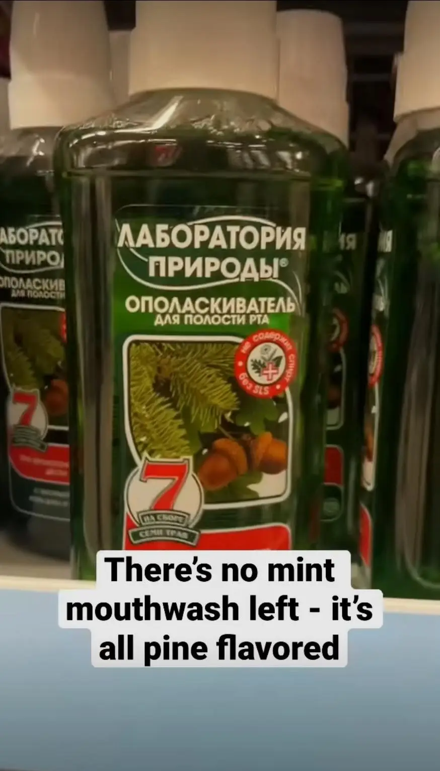 A close-up shot of green bottles of 'Laboratory of Nature' mouthwash on a store shelf, featuring pine needles and acorns on…