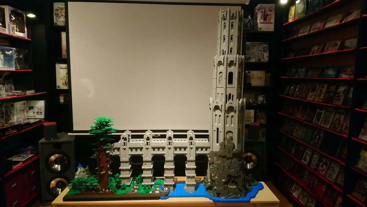 A large, intricate white Lego castle model with a tall tower and a green tree stands on a wooden table in front of a blank…