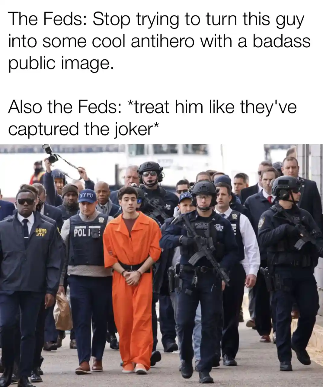 A man in an orange jumpsuit is being escorted by numerous heavily armed police officers in tactical gear. The overlaid text…
