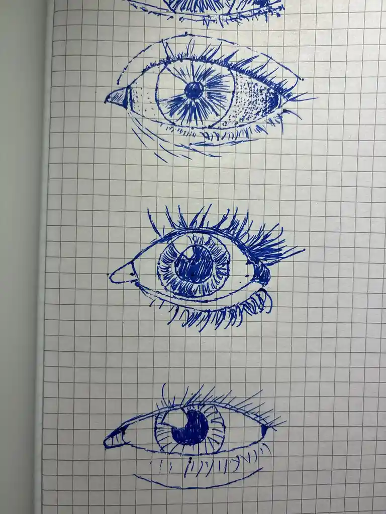 Three hand-drawn blue ink sketches of eyes on graph paper, each progressively more stylized and less realistic. The top eye…