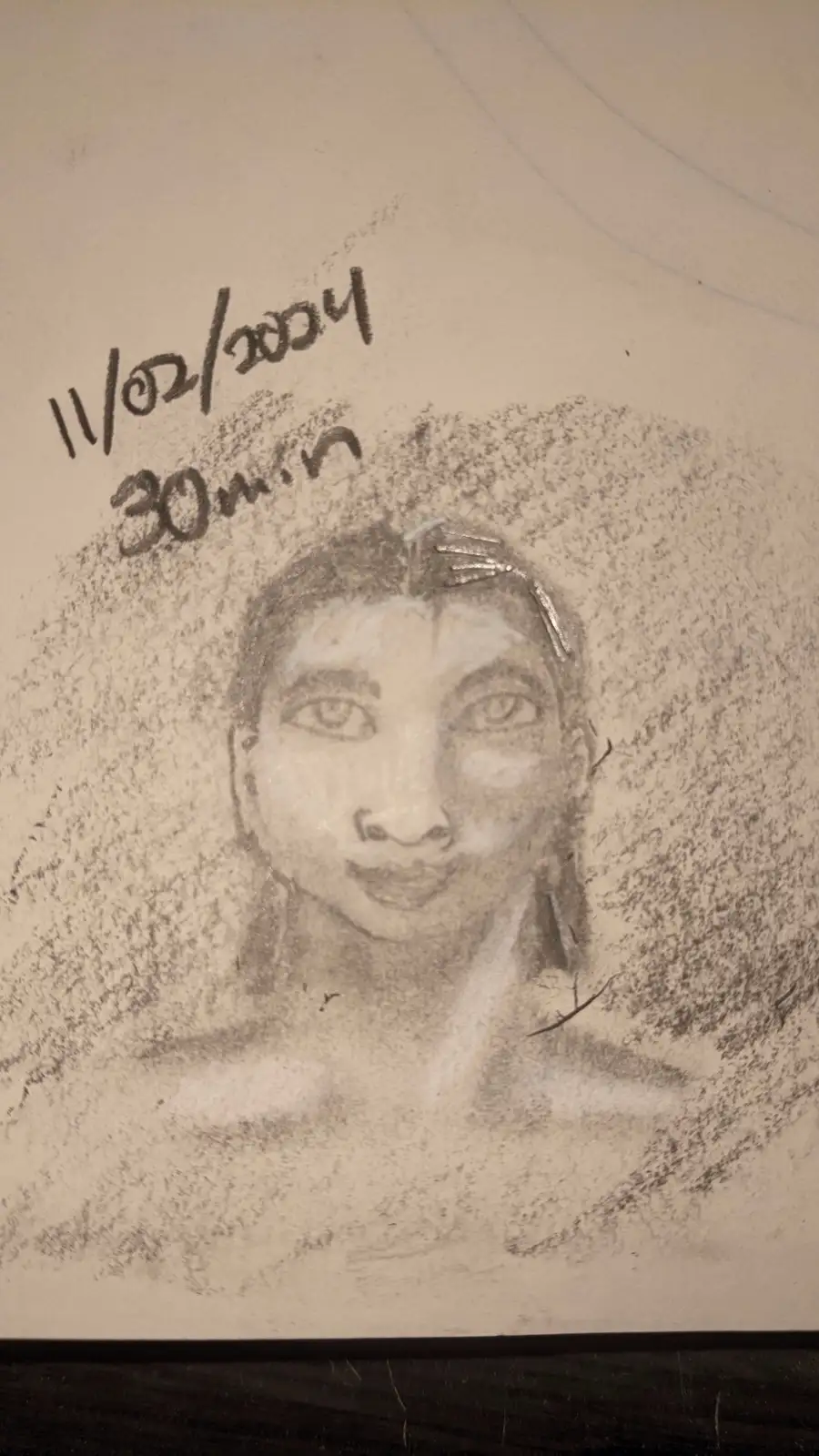 A pencil sketch of a person's face and shoulders on paper, with handwritten text in the upper left corner reading…