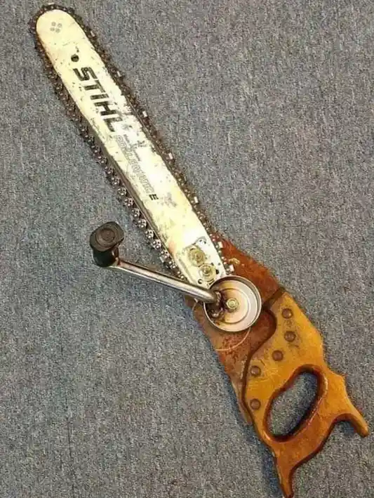 A heavily used Stihl chainsaw bar with a rusty chain is visibly attached to the blade of a vintage wooden hand saw, creating…