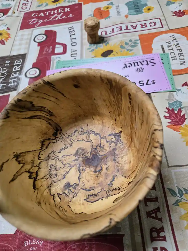 A wooden bowl with a natural wood grain pattern that resembles a map of the United States, placed on a fall-themed…