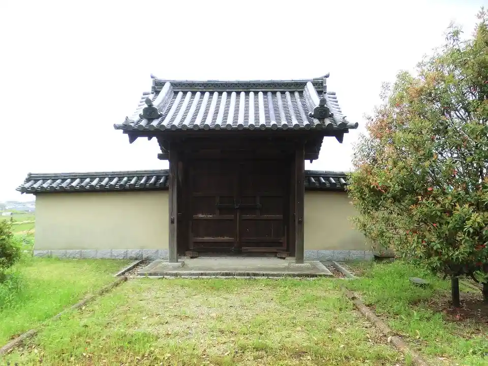 a traditional japanese temple gate with a tiled roof and wooden doors, set in a grassy area with trees nearby, overlaid with…