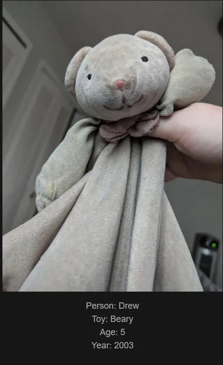 A close-up photo shows a hand holding a worn, beige plush teddy bear with a soft fabric body and a pink nose, identified by…