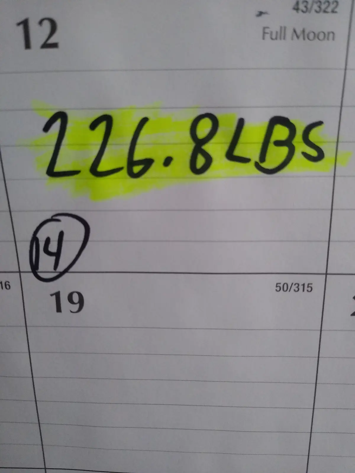 A close-up of a lined calendar page showing the date '12' with '226.8LBS' handwritten in black ink and highlighted in…