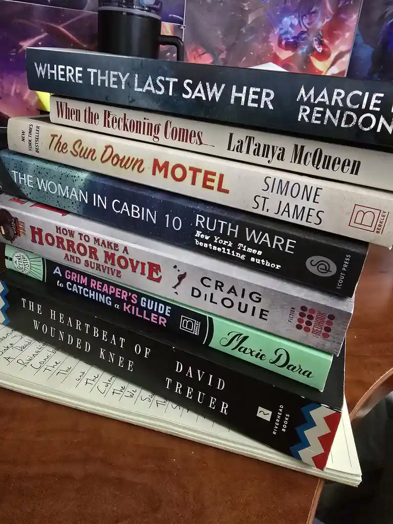 A stack of horror and thriller novels with titles like 'Where They Last Saw Her,' 'The Sun Down Motel,' and 'How to Make a…