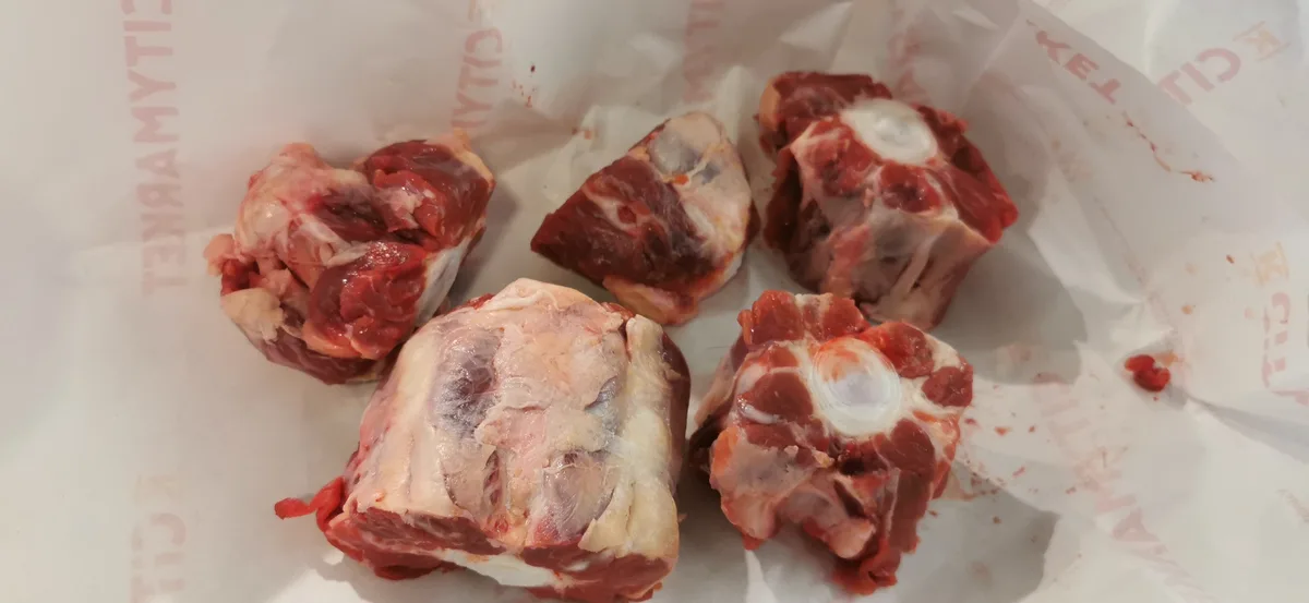 Five raw beef bones, likely marrow bones, are arranged on white paper with faint 'CITYMARKET' branding. The overlaid text…