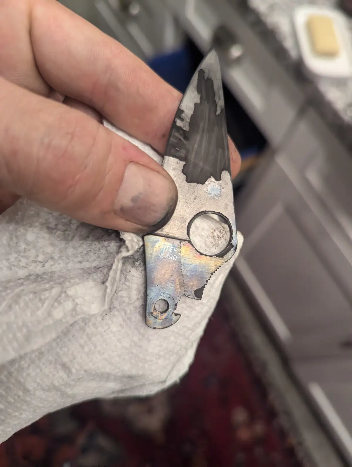A hand holds a severely damaged Spyderco knife, its blade and handle visibly melted and charred, with the brand name and…