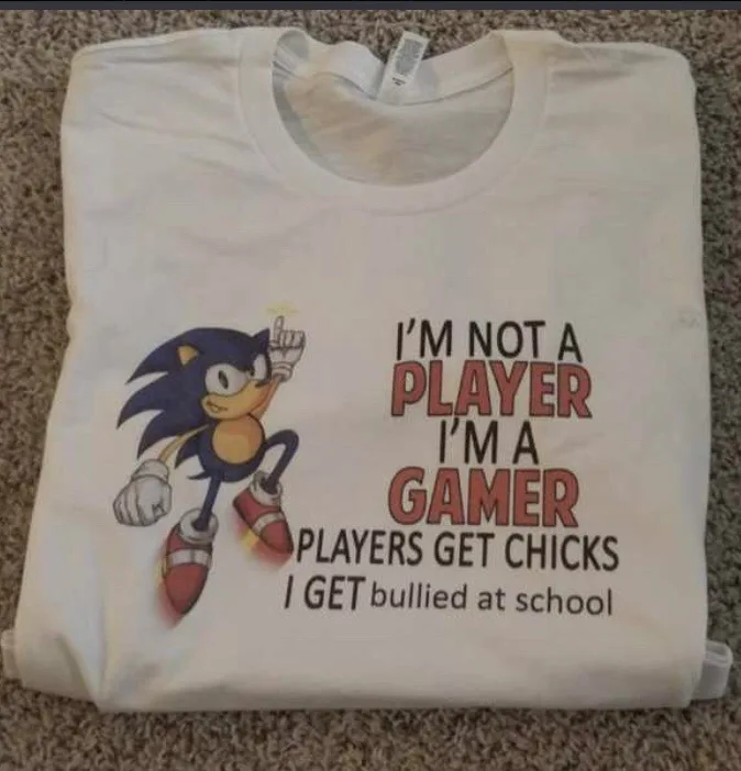 A folded white t-shirt displays a graphic of the blue hedgehog Sonic the Hedgehog pointing upward. Beside him, bold text…