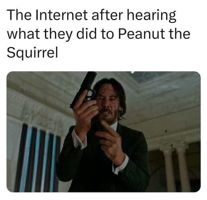 A still image of Keanu Reeves as John Wick holding a pistol, looking intensely at the camera with a grim expression. The…