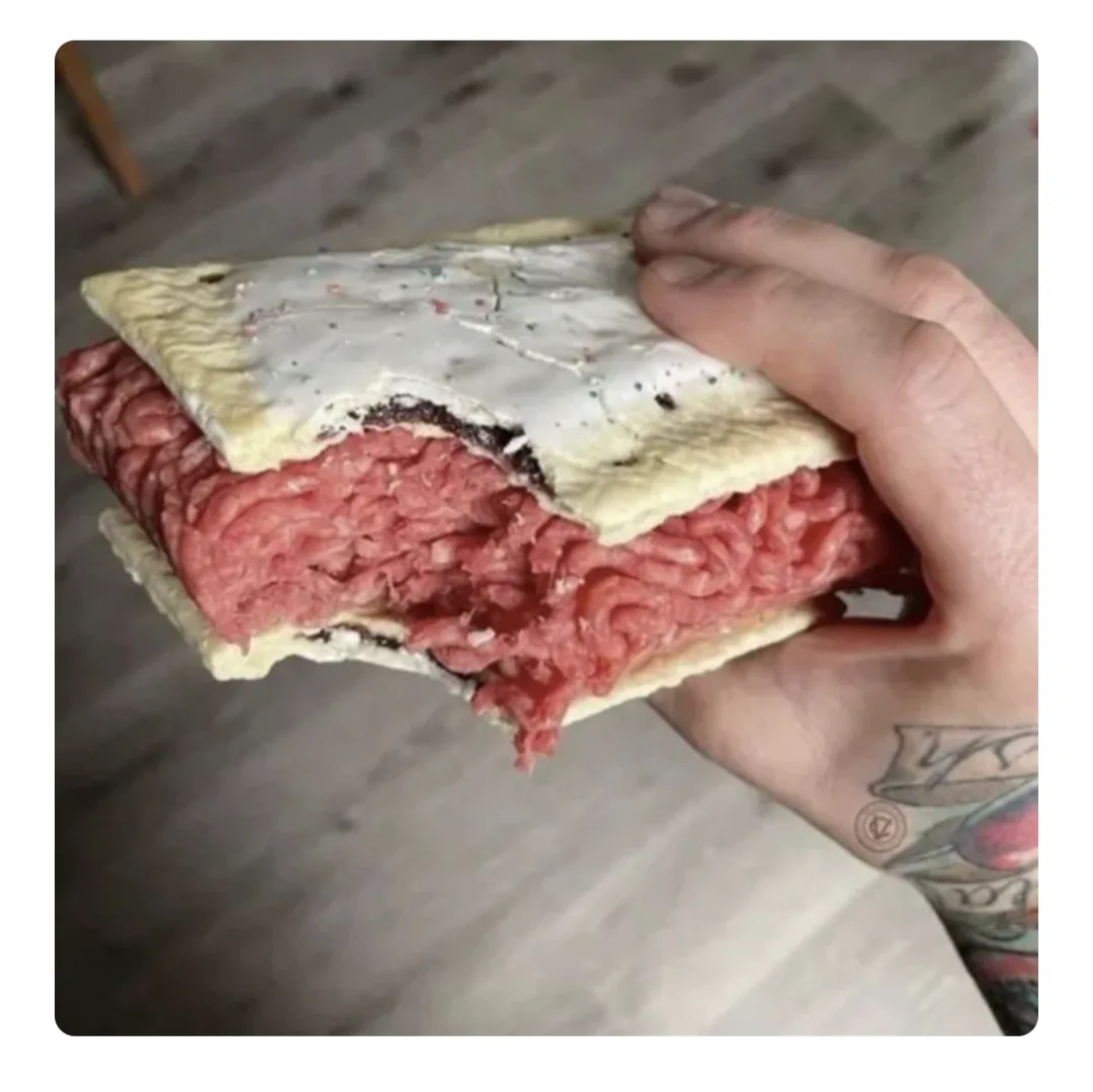 a hand holds a partially eaten pop tart that has been crudely altered to look like it contains raw ground meat instead of…