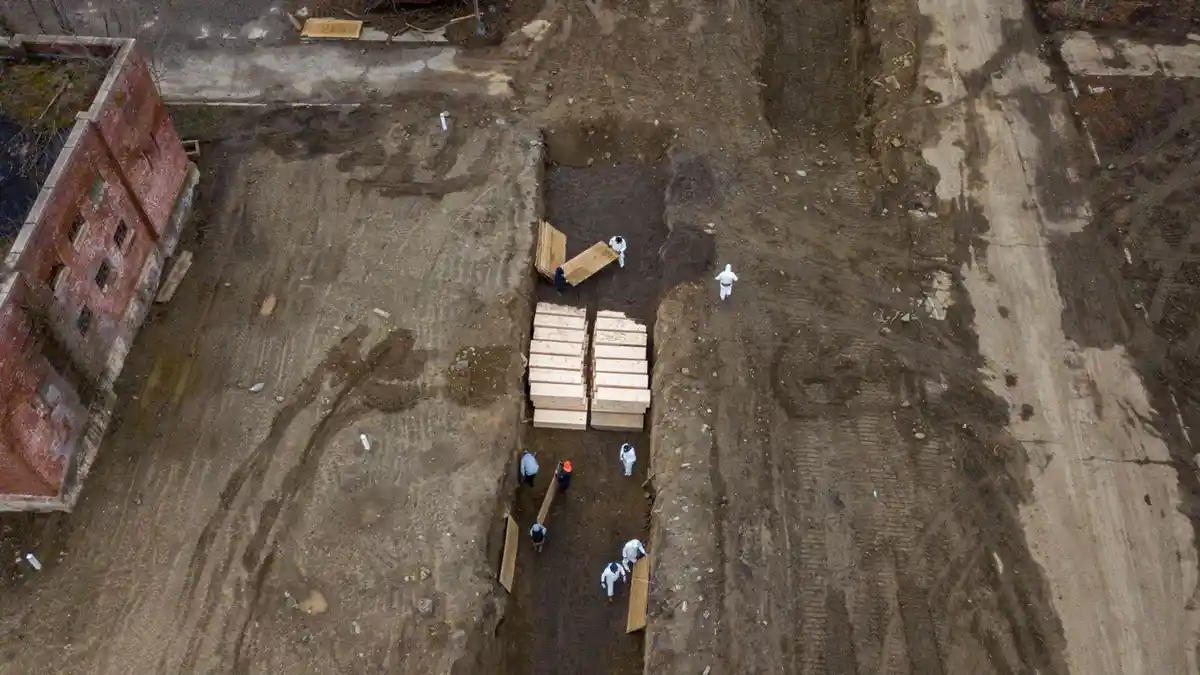 An aerial view shows workers in white hazmat suits and others in regular work clothes moving wooden planks at a construction…