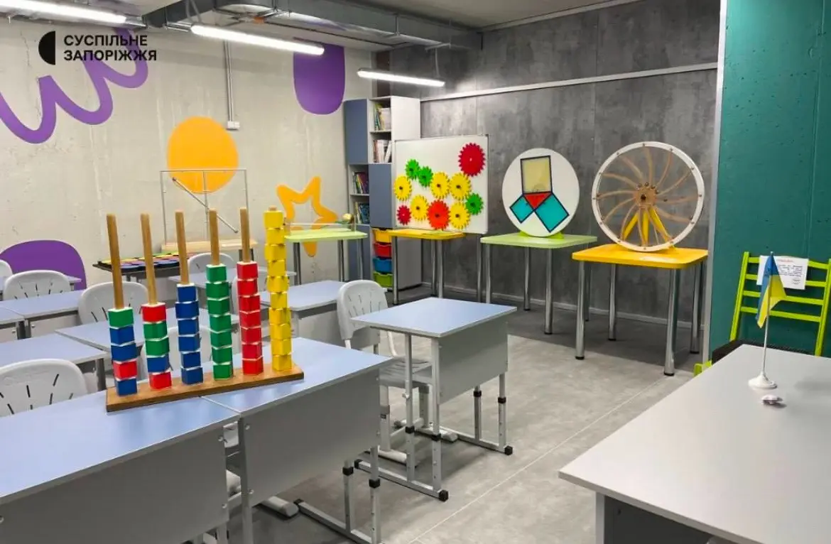 A brightly lit, modern classroom filled with colorful educational toys like stacking rings, geometric puzzles, and a large…
