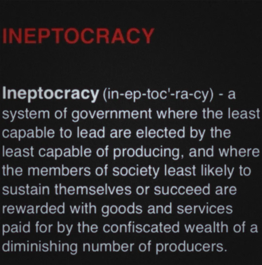 The image displays a black background with red and white text defining the term 'Ineptocracy' as a satirical political…