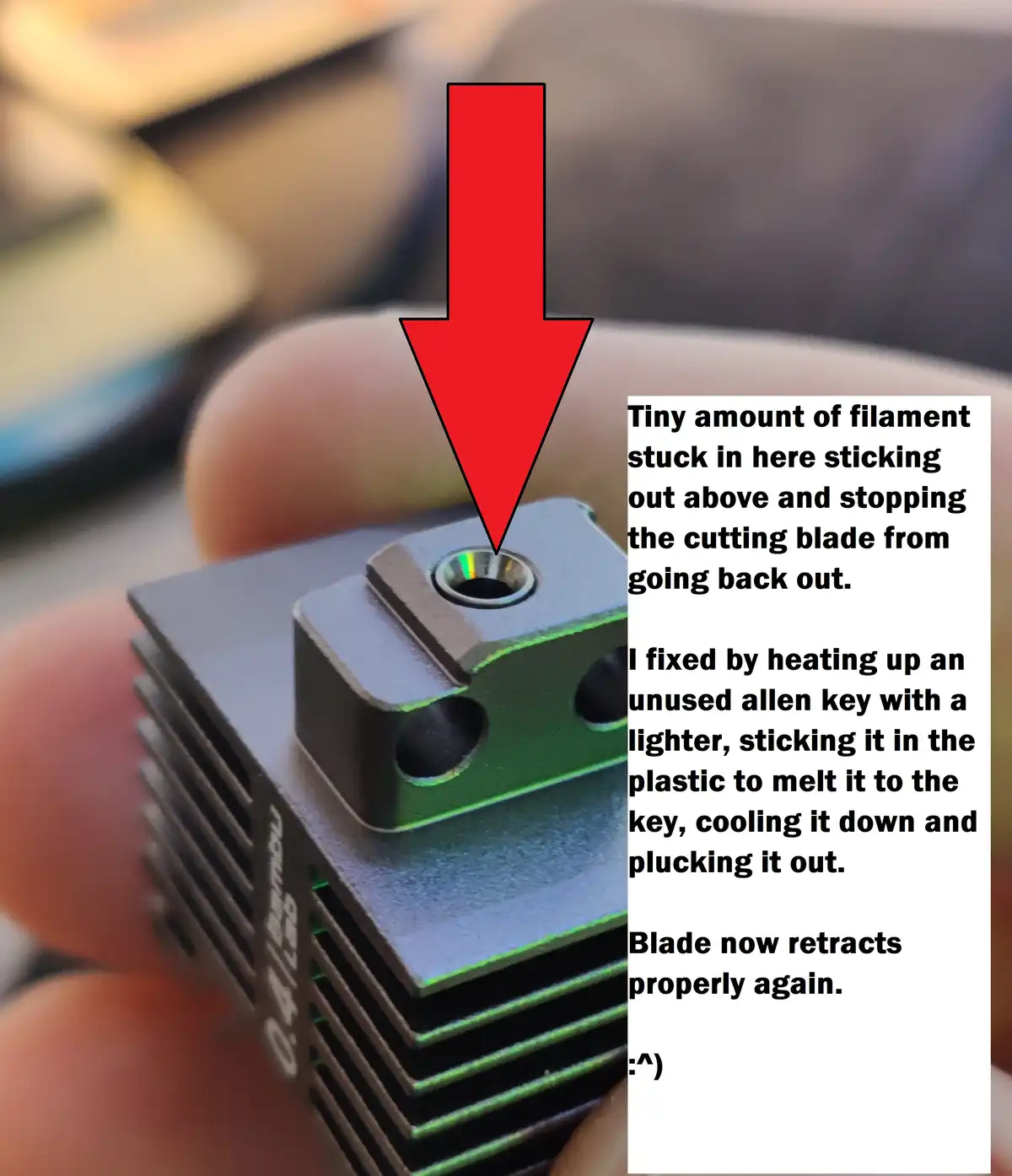 A close-up photo shows a person's fingers holding a small, green and black 3D printer component with a hole. A large red…
