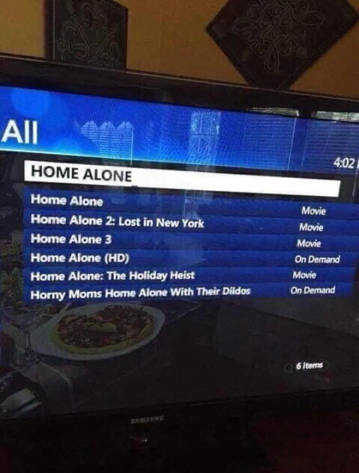 A TV screen displays a movie listing under 'HOME ALONE', showing titles like 'Home Alone 2: Lost in New York' and 'Home…