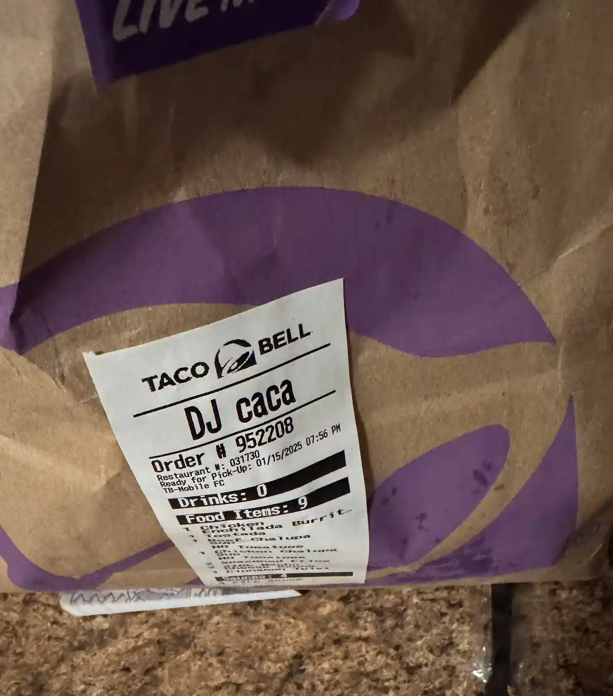 A close-up of a Taco Bell paper bag with a receipt attached, showing the customer name 'DJ caca' and an order with 9 food…