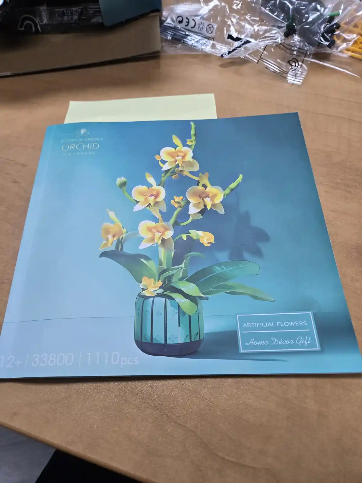 A close-up photo shows a puzzle box for a 33800-piece 'Botanical Garden Orchid' puzzle, featuring an image of a yellow…