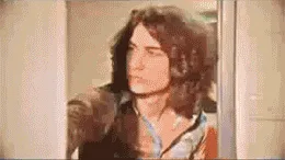 A sequence of six frames shows a man with long curly hair and a patterned shirt reacting with increasing shock and horror…