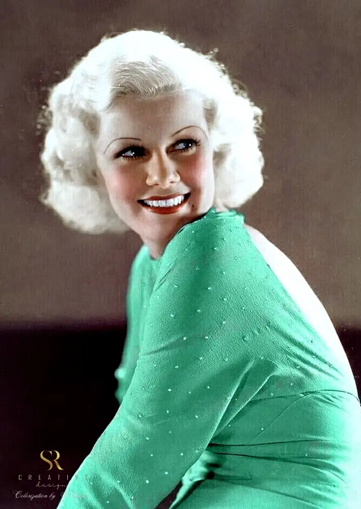 A vintage colorized portrait of a smiling woman with platinum blonde curls and red lipstick, wearing a green dress with…