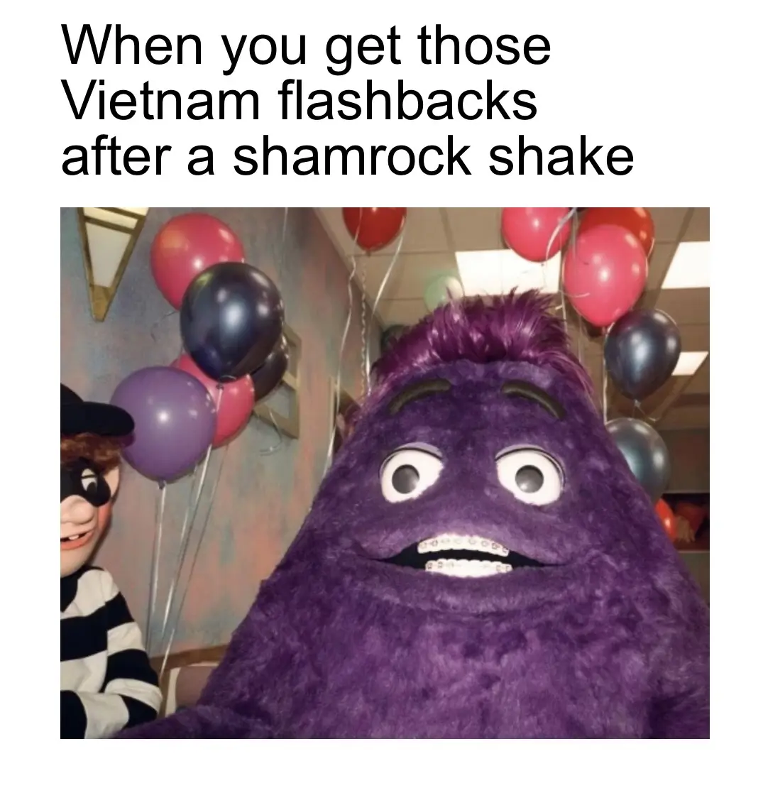 A close-up photo shows a large, purple, furry mascot with wide, startled eyes and visible braces, looking directly at the…