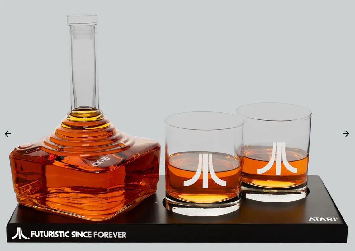 A product photo shows a square decanter and two tumblers filled with amber liquid, all branded with the Atari logo. The…