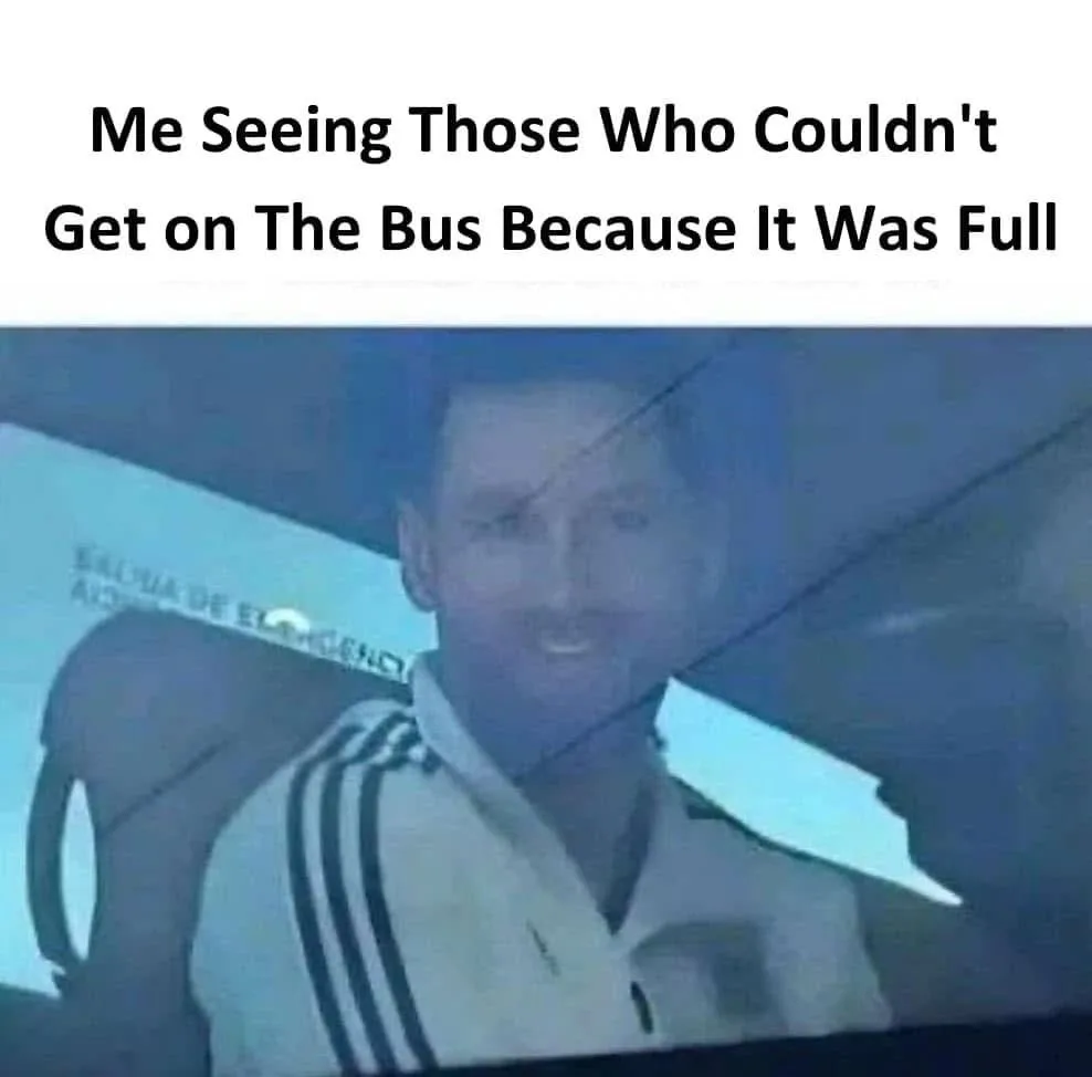 A man in a white Adidas tracksuit with three black stripes on the sleeves is shown smiling while seated inside a vehicle…