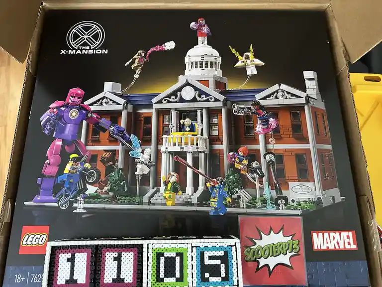 The image shows the front of a LEGO Marvel X-Mansion set box, featuring a large illustration of the mansion with multiple…