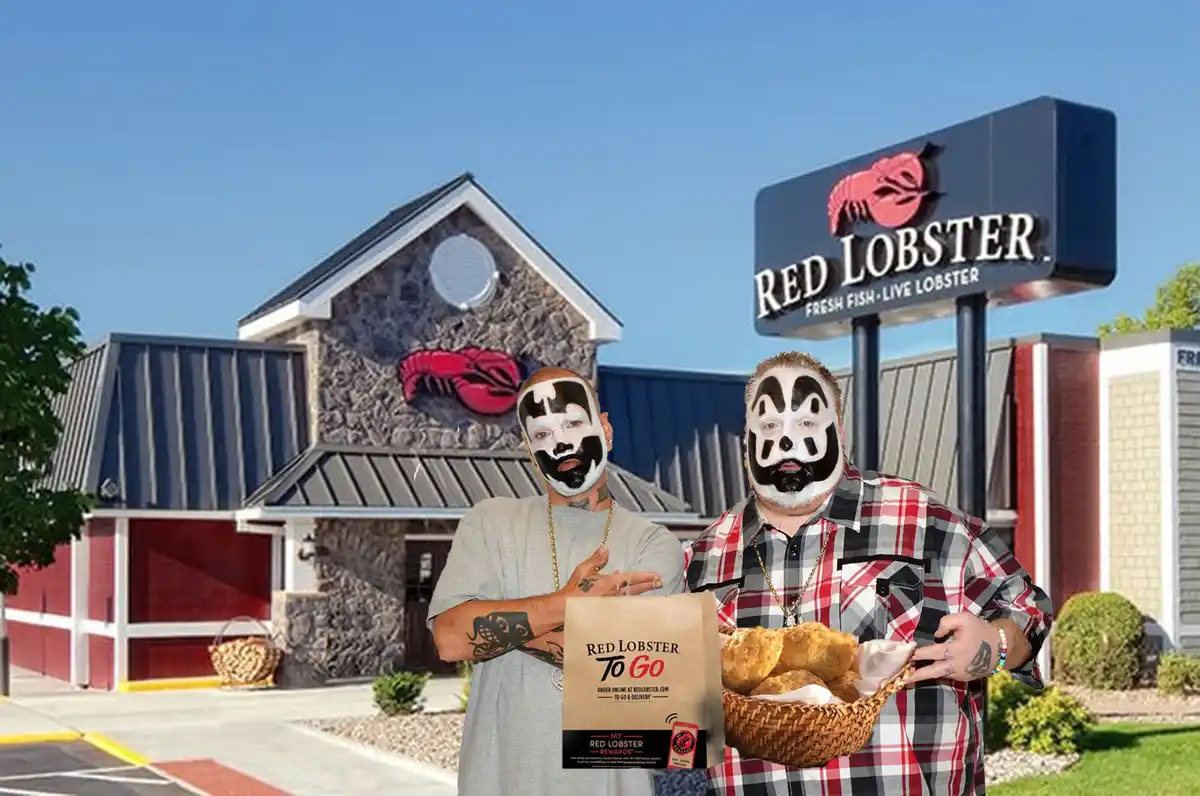 Two men with black-and-white face paint resembling WWE wrestlers stand in front of a Red Lobster restaurant, one holding a…