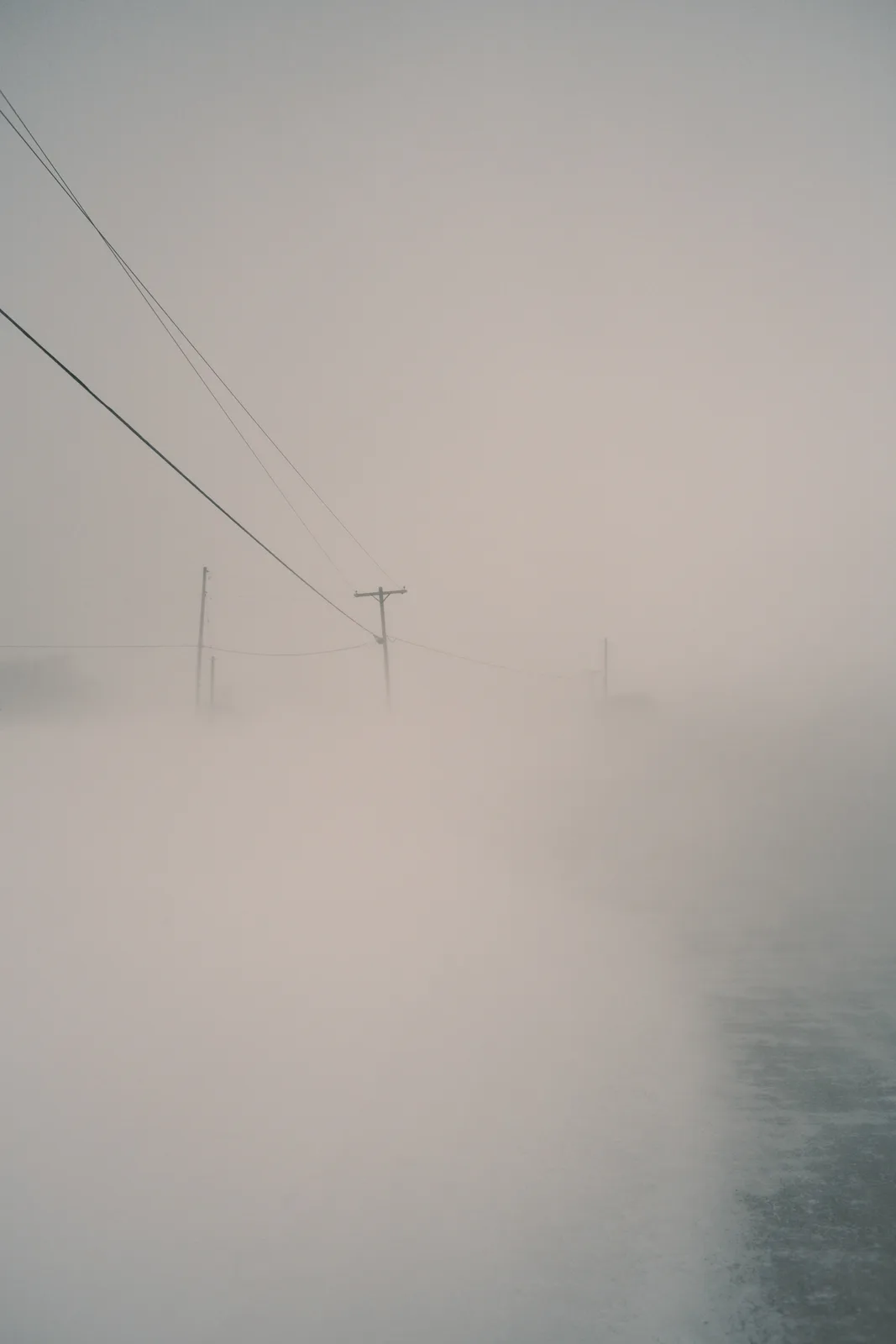 A desaturated, foggy landscape with utility poles and wires barely visible through thick mist, with the overlaid text 'i'm…