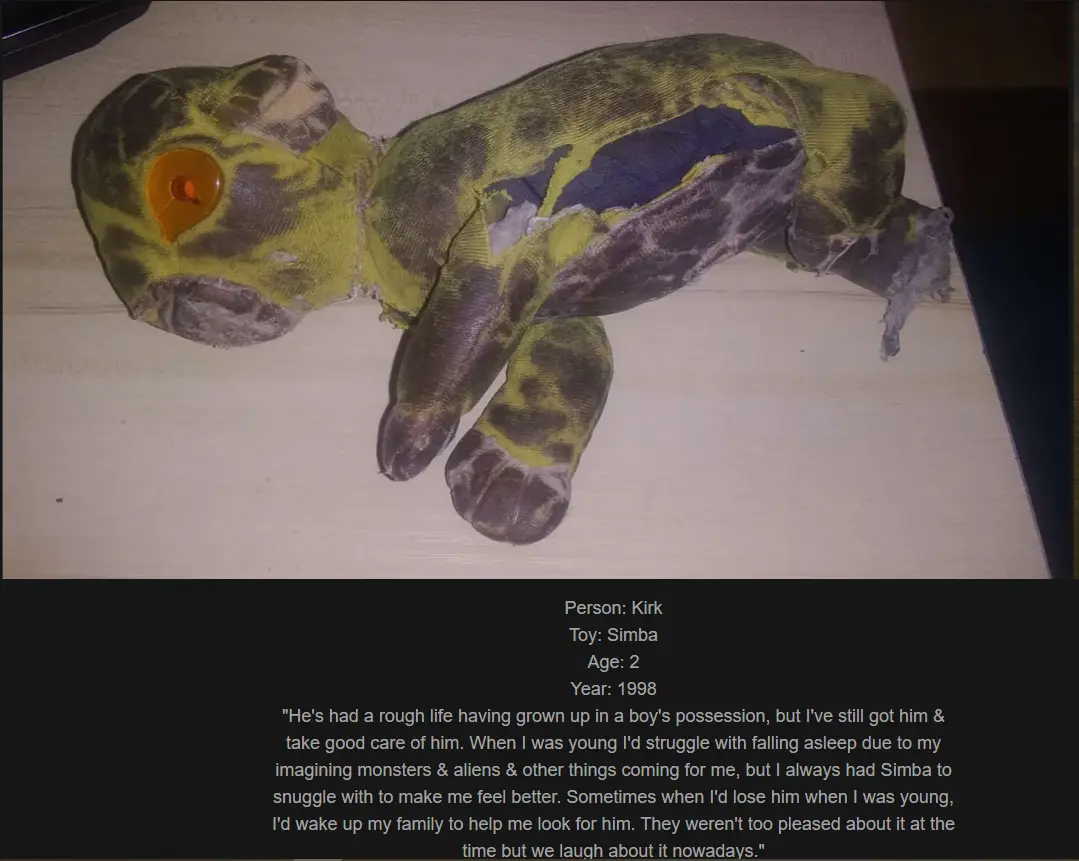 A heavily worn, torn, and stained green and brown plush toy resembling a small animal lies on a wooden surface. Overlaid…