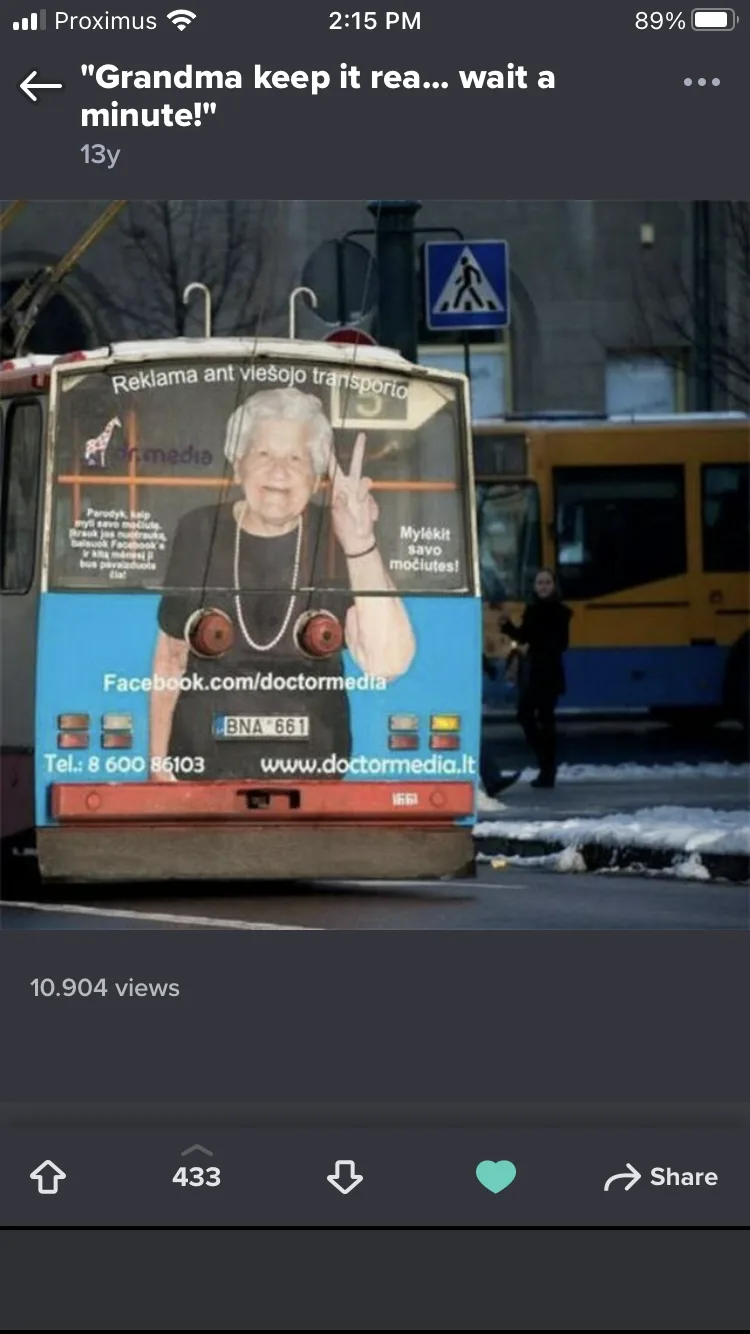 The image shows the rear of a public bus with a large advertisement featuring a smiling elderly woman making a peace sign…