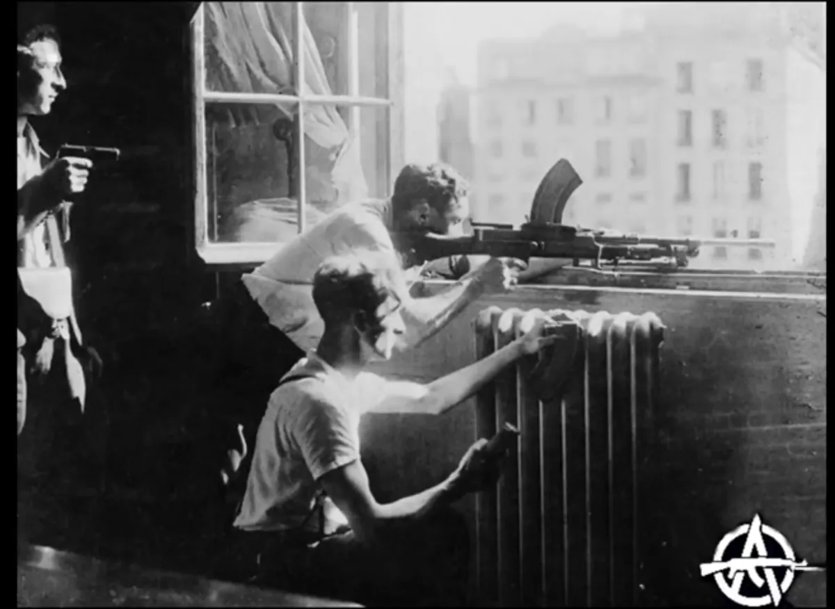 A black-and-white historical photo shows three men in an apartment, one aiming a rifle from a window, another holding a…