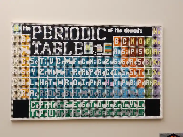A large, wall-mounted periodic table constructed from colorful LEGO bricks, displaying element symbols and names in a grid…