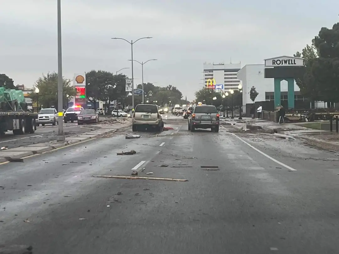 A street scene shows debris scattered across a wet road with cars stopped, a Shell gas station, a McDonald's, and a large…