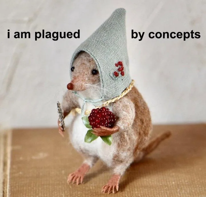 A small, handcrafted felted mouse wearing a grey knitted pointy hat with red berry embroidery and a yellow rope necklace. It…