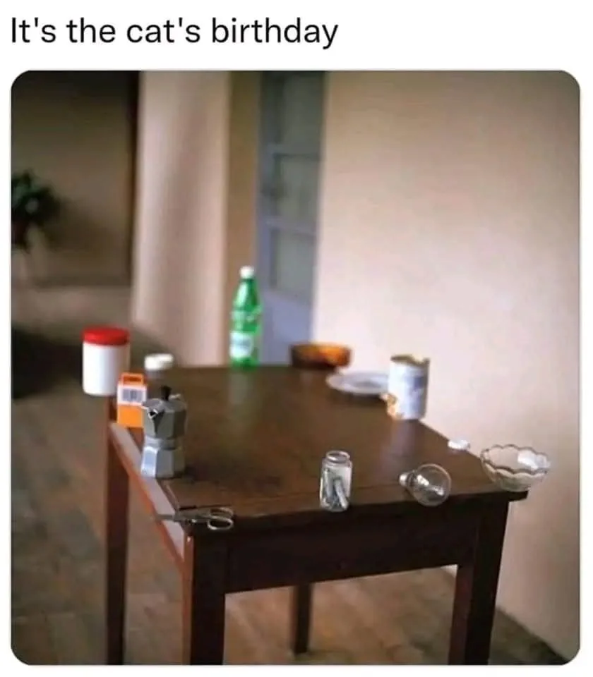A wooden table is set with miniature household items including a tiny coffee maker, scissors, jars, a bowl, and a bottle…