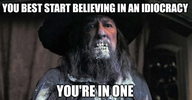 A close-up image of a man with a long beard, wearing a dark hat, and showing a grimacing, teeth-baring expression. The text…
